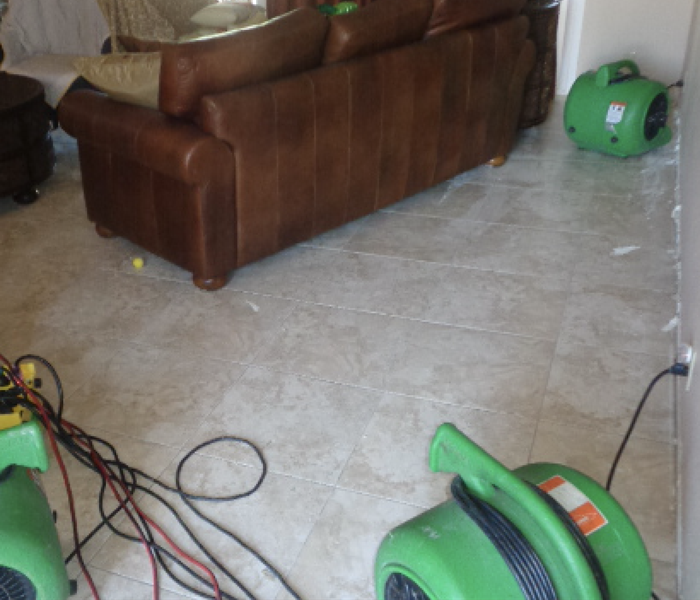 Living room with sofa moved away from wall and green drying equipment 