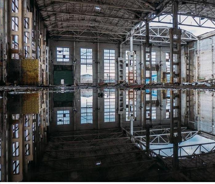 Inside of flooded dirty abandoned ruined industrial building with water reflection of interior.