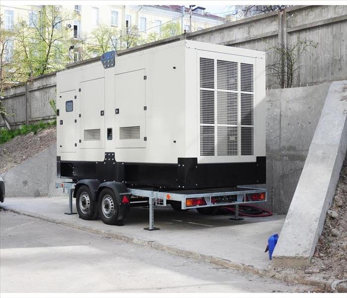 Commercial grade generator on a trailer parked at the back of a commercial building