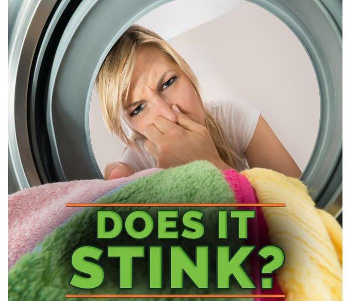 A woman covering her nose because her washing machine smells bad